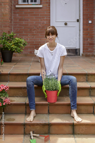 Mujer joven con plantas delante de su casa photo