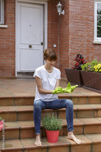 Mujer joven con plantas delante de su casa photo