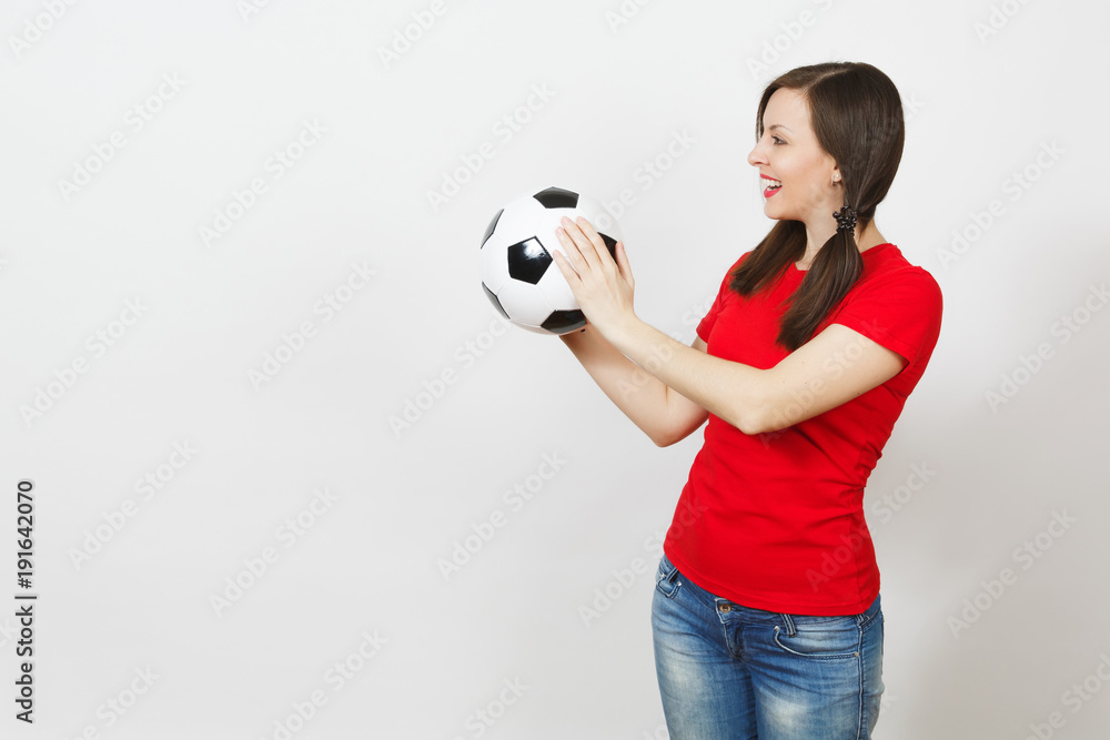 Smiling European young woman, two fun pony tails, football fan or player in red uniform hold classic soccer ball isolated on white background. Sport play football, healthy lifestyle concept. Side view Smiling European young woman, two fun pony tails, football fan or player in red uniform hold classic soccer ball isolated on white background. Sport play football, healthy lifestyle concept. Side view
