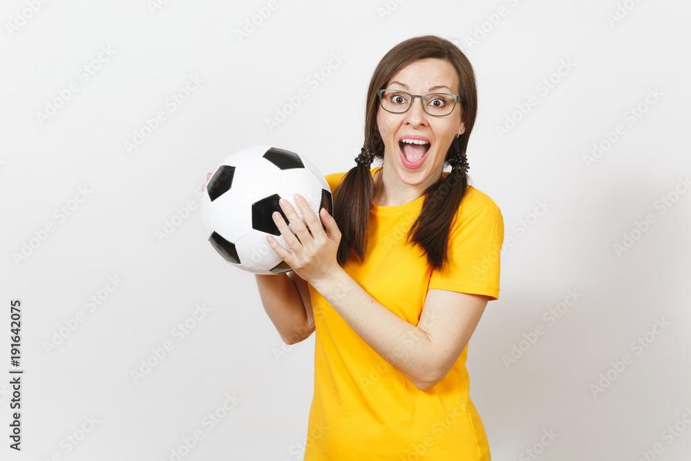 Smiling European woman, two fun pony tails, football fan or player in glasses, yellow uniform hold classic soccer ball isolated on white background. Sport, play, football, healthy lifestyle concept. Smiling European woman, two fun pony tails, football fan or player in glasses, yellow uniform hold classic soccer ball isolated on white background. Sport, play, football, healthy lifestyle concept.