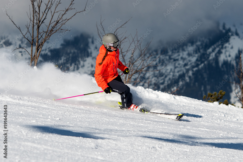 Junge Frau auf einer Skipiste bei der Abfahrt ins Tal