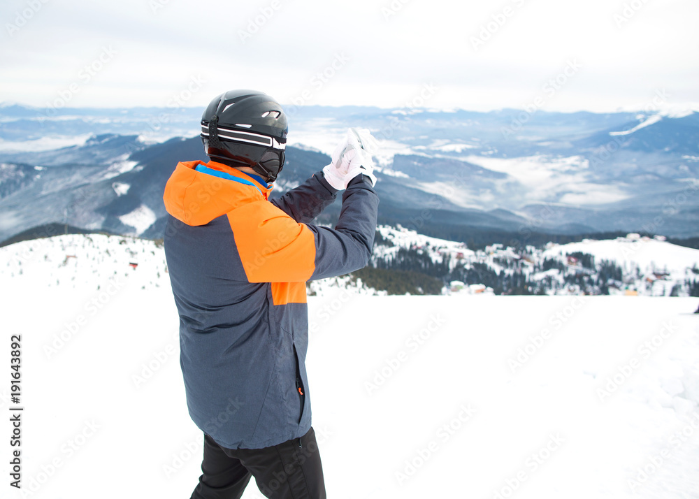 .tourist skier on top of a mountain wearing a helmet, happy with victories