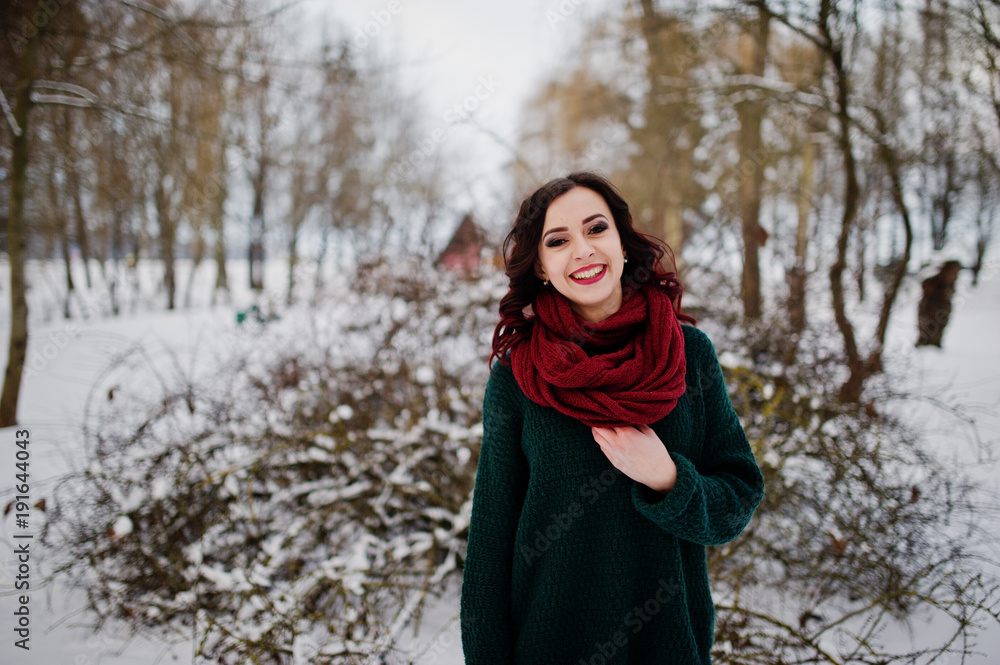 Brunette girl in green sweater and red scarf outdoor on evening winter day. Brunette girl in green sweater and red scarf outdoor on evening winter day.