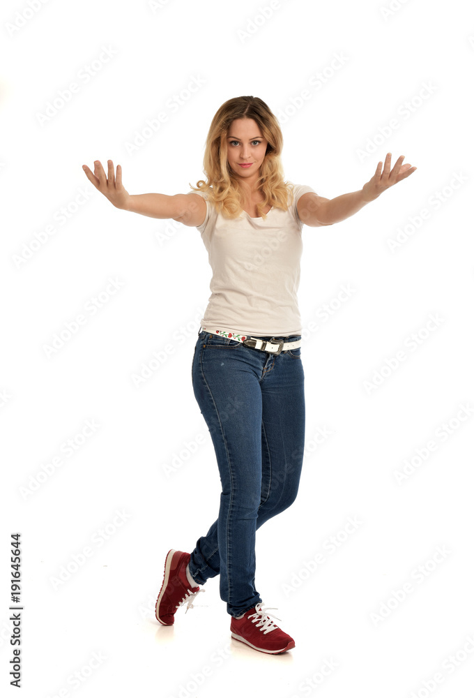 full length portrait of blonde girl wearing white shirt and jeans. standing pose, isolated on white studio background. full length portrait of blonde girl wearing white shirt and jeans. standing pose, isolated on white studio background.