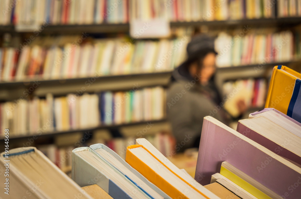 Naklejka premium Lesen Kundin im secondhand Buchladen - Reading Customer in secondhand bookstore