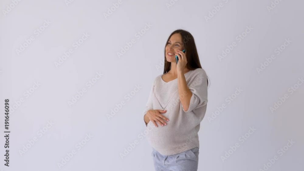 Smiling woman holding a telephone to her pregnant belly Smiling woman holding a telephone to her pregnant belly