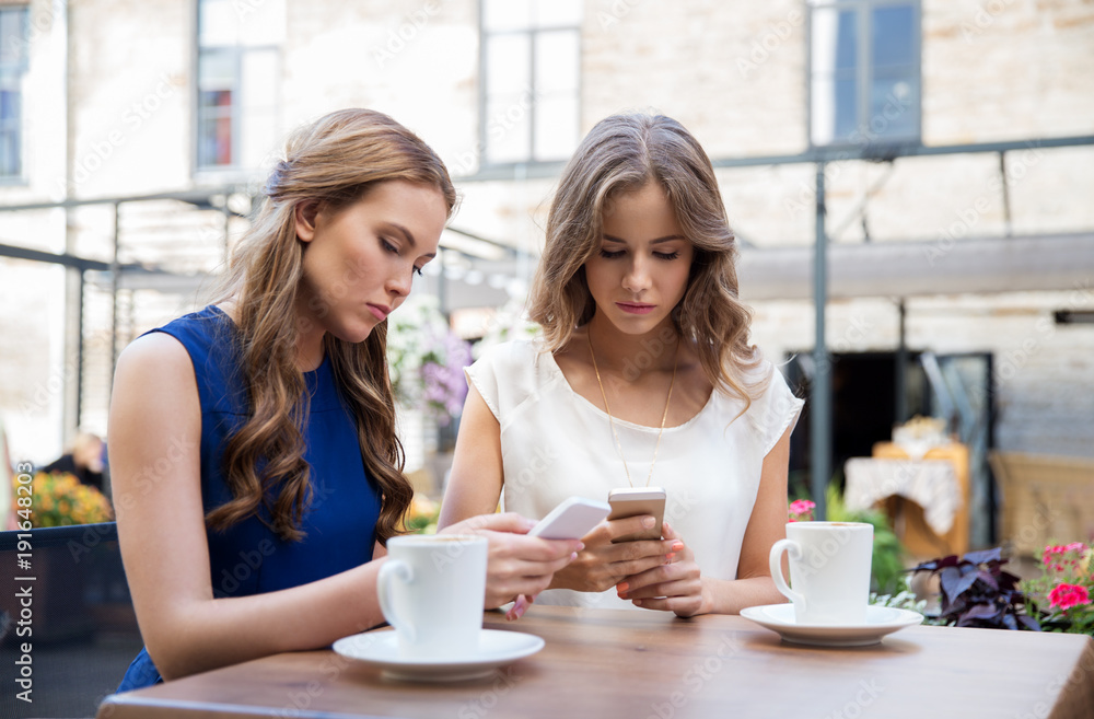 young women with smartphones and coffee at cafe young women with smartphones and coffee at cafe