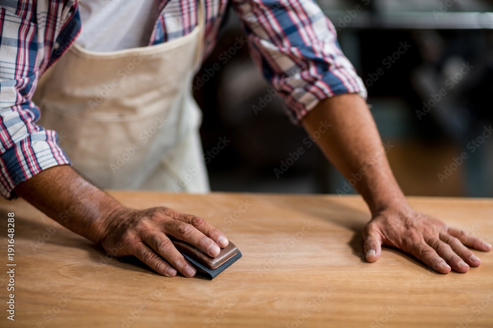 Carpenter rubbing wood with sanding block Carpenter rubbing wood with sanding block