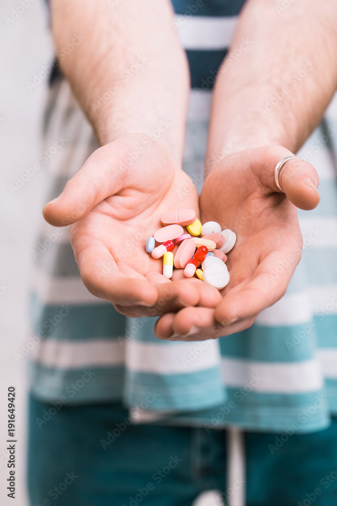 Closeup of a man holding colorful pills in his right hand Closeup of a man holding colorful pills in his right hand