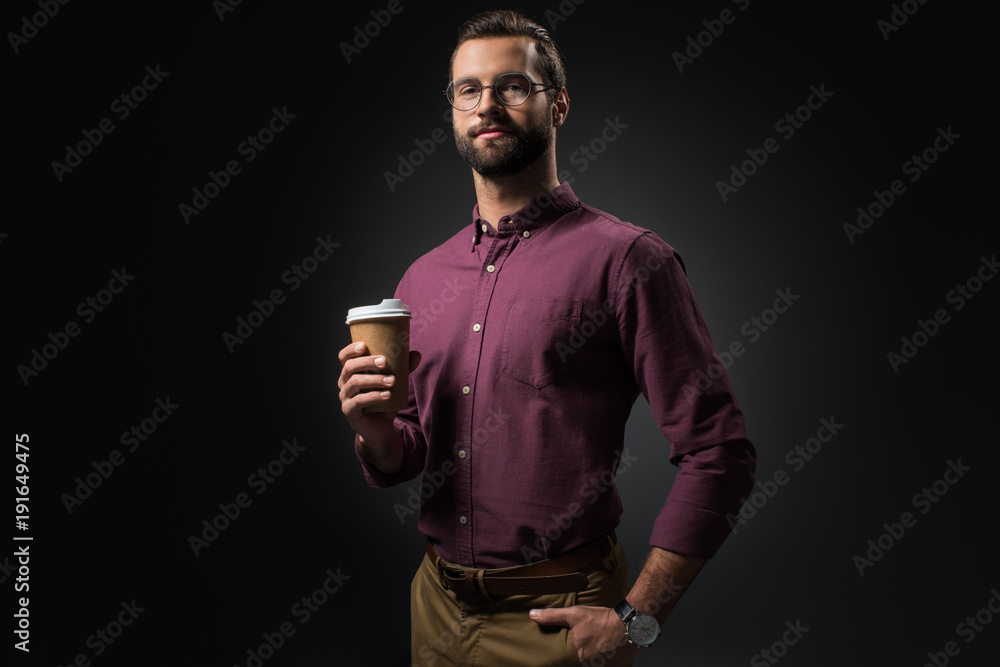 portrait of businessman in eyeglasses with coffee to go isolated on black
