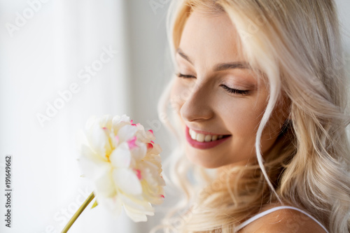 close up of beautiful young woman smelling flower