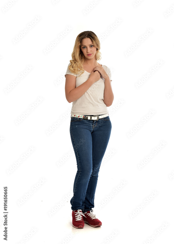 full length portrait of blonde girl wearing white shirt and jeans. standing pose, isolated on white studio background. full length portrait of blonde girl wearing white shirt and jeans. standing pose, isolated on white studio background.