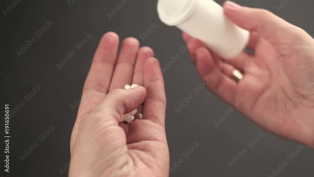 pills poured into a hand from a jar, close-up of female hands on a black background pills poured into a hand from a jar, close-up of female hands on a black background
