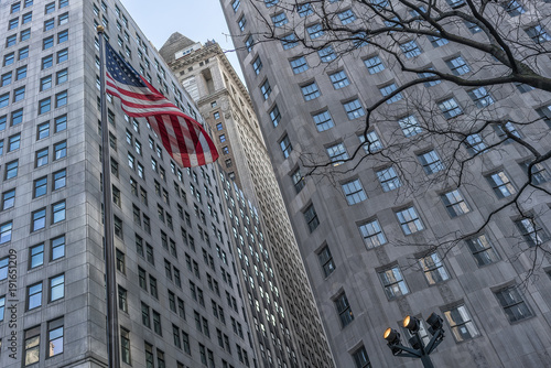 American flag with buildings behind.