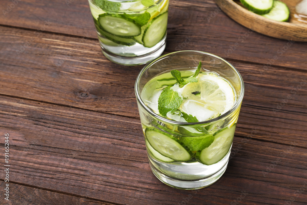 Detox drink with cucumber, lemon and mint in glasses on a wooden background. Copy space. Food background Detox drink with cucumber, lemon and mint in glasses on a wooden background. Copy space. Food background
