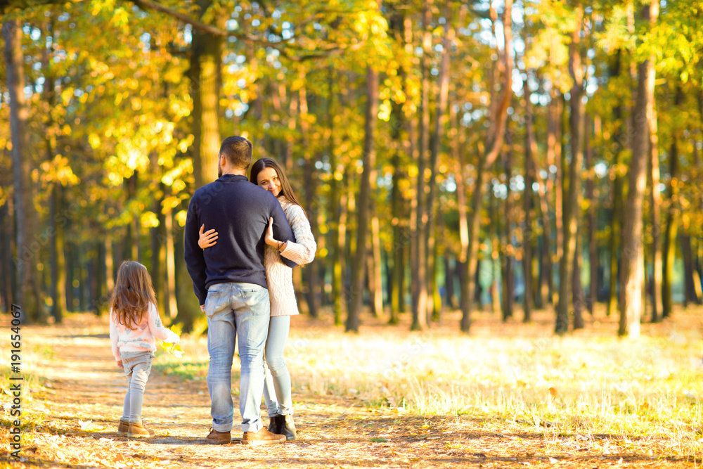 Fototapeta premium mom and dad with daughter at sunset playing