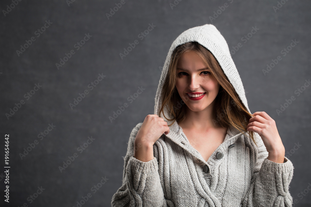 Portrait of beautiful girl in gray sweater playing with her hair, indoor shot in the gray background Portrait of beautiful girl in gray sweater playing with her hair, indoor shot in the gray background