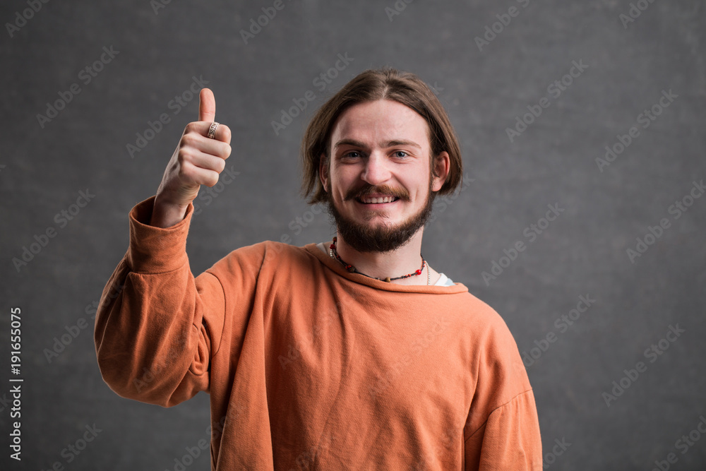 Portrait of male blogger, bearded happy man showing thumb up in the gray background Portrait of male blogger, bearded happy man showing thumb up in the gray background
