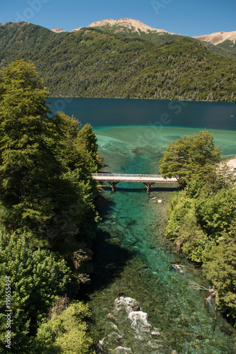 Portrait of a turquoise river rising from a lake and mountains in the background