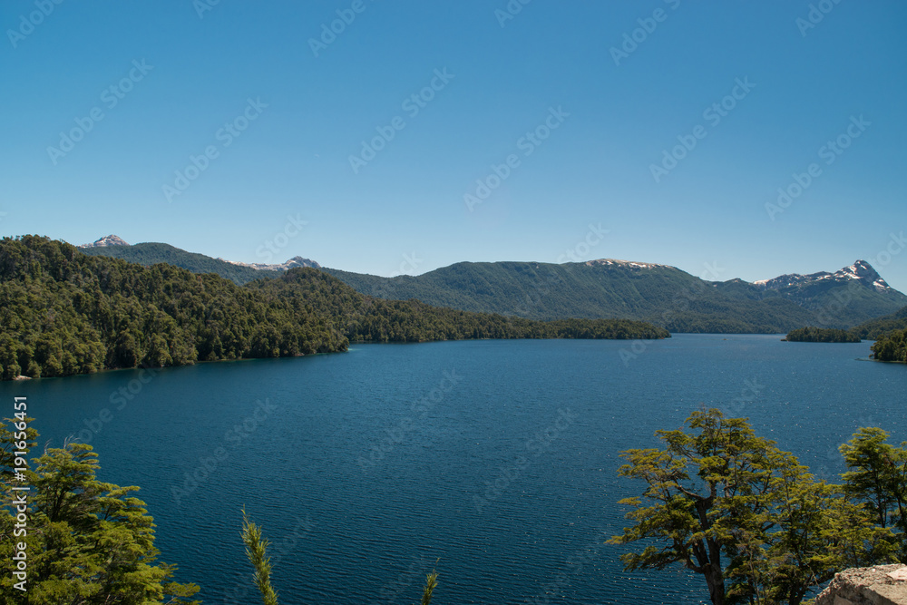 Naklejka premium Landscape of a lake with island, with snowy mountain and blue sky