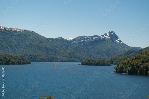 Landscape of a lake with island, with snowy mountain and blue sky