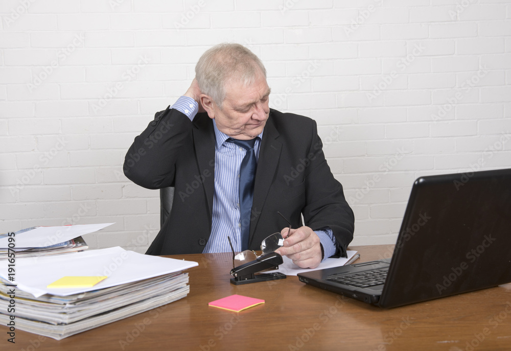 Stressed mature man at work looking at a laptop, sitting at a desk Stressed mature man at work looking at a laptop, sitting at a desk