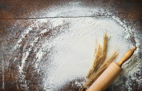 Baking background with the rolling pin, wheat and flour on the wooden table