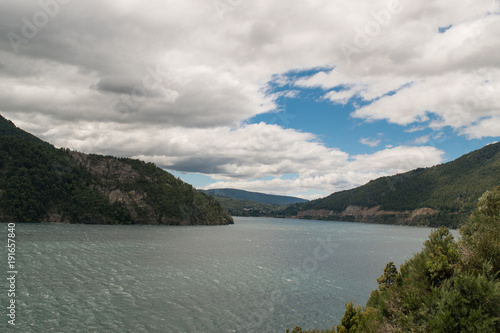 Lake landscape on cloudy day with mountains and pines