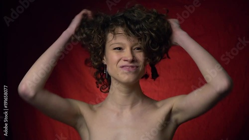 Curly brunette gaily touches her hair