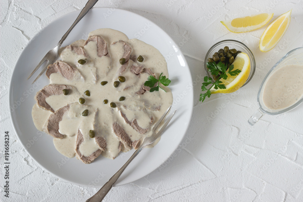 Vitello tonnato is a traditional italian dish on a white concrete background.