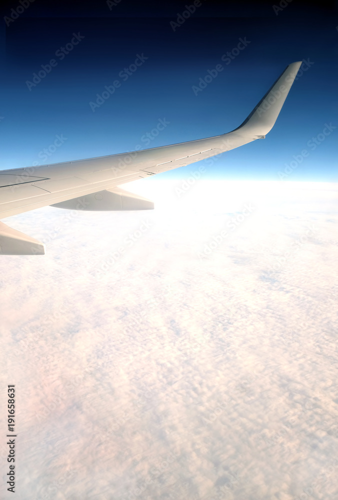 Fototapeta premium Beautiful top view from passenger supersonic airplane window flying high above white clouds in blue sky
