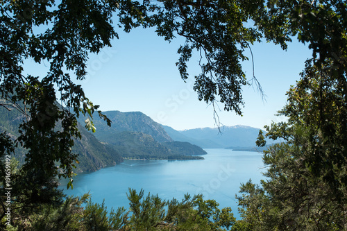 Photo from height  surrounded by trees  with lake and mountains in the background