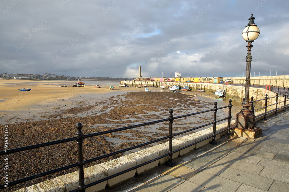 Margate Harbor Arm with mooring boats, the lighthouse and the beach at low tide, Margate, Kent, UK