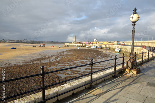 Margate Harbor Arm with mooring boats, the lighthouse and the beach at low tide, Margate, Kent, UK photo