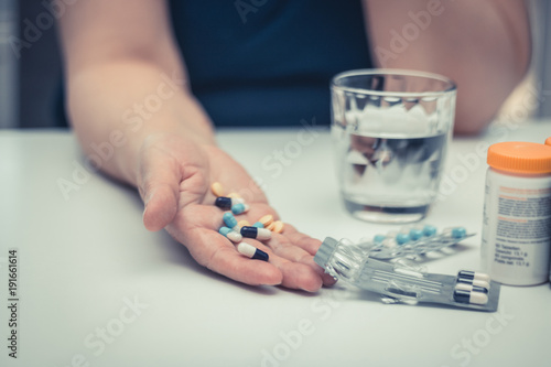Hand of mature woman full of pills and medicines.
