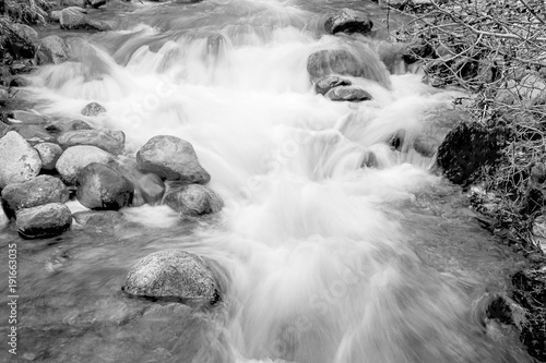 Black and White imate of a creek in full flow and softened photo