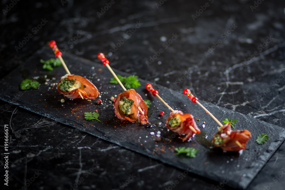 Φωτογραφία parma ham and cheese skewers with olive oil on black plate with salt and pepperc