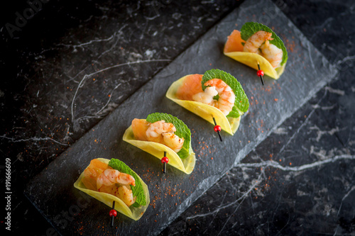 Obraz na płótnie shrimp appetizers on black plate w salonie