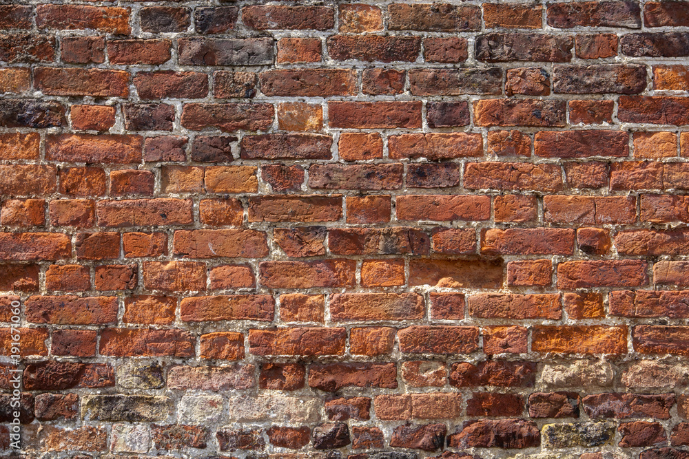 Obraz premium An old weathered, damaged, badly repaired red brick wall full frame