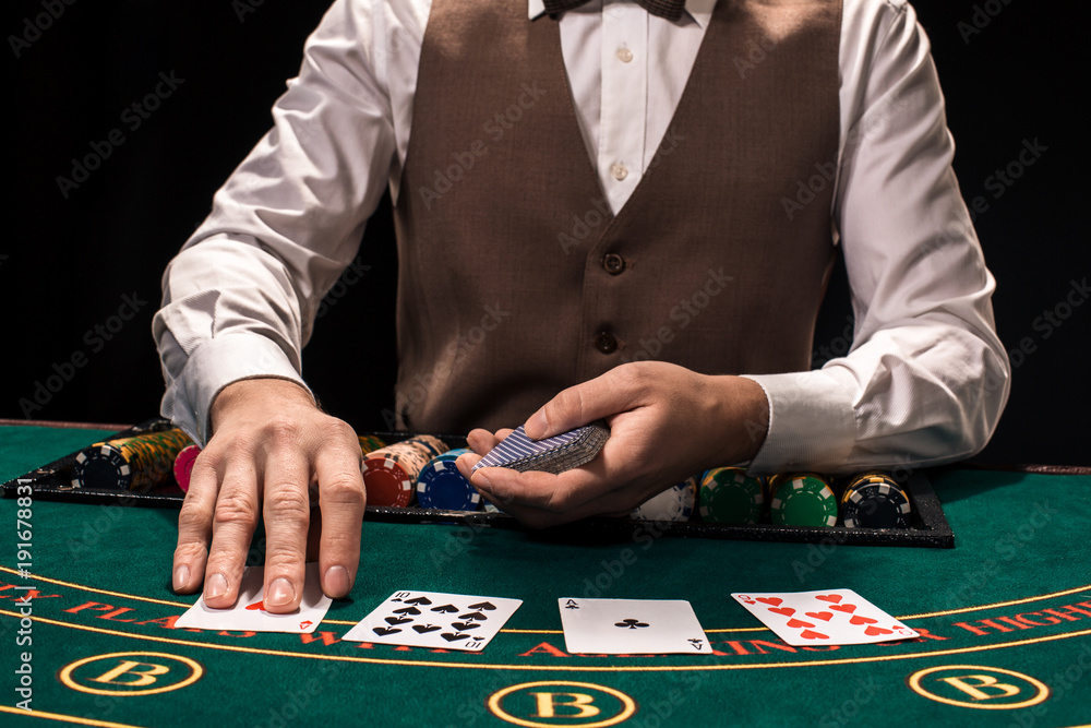 Close up of holdem dealer with playing cards and chips on green table Close up of holdem dealer with playing cards and chips on green table