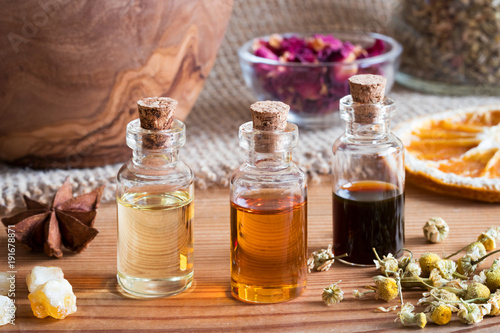 Bottles of essential oil with star anise, chamomile and frankincense