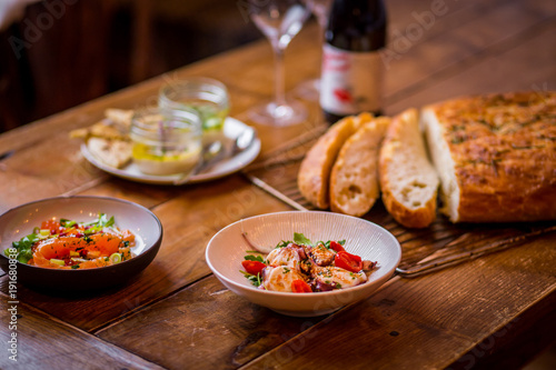 assorted salads in mediterranean restaurant with focaccia bread in background on wooden table