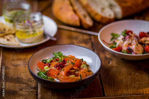 assorted salads in mediterranean restaurant with focaccia bread in background on wooden table