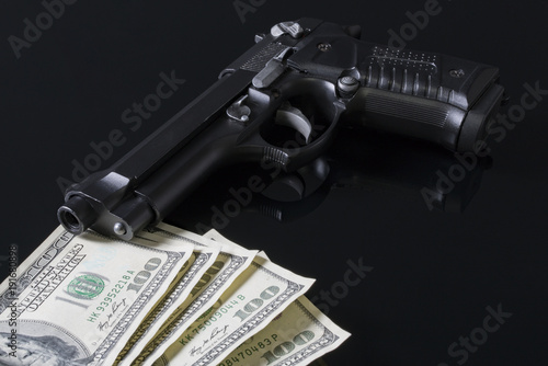 Silah ve para siyah zemin üstünde photo
