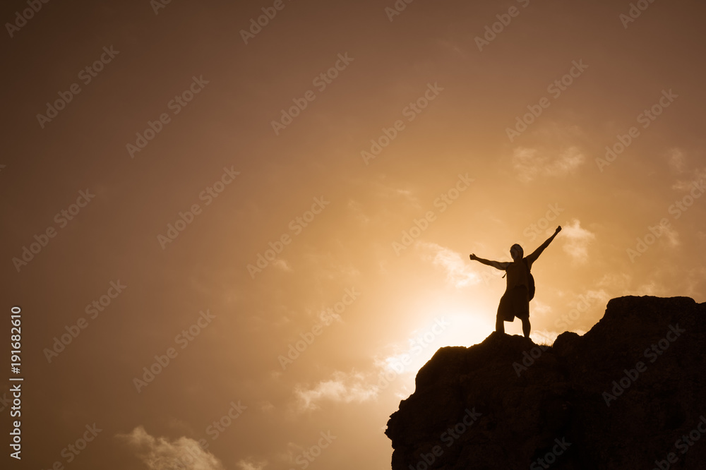 Man standing on top a mountain feeling free.