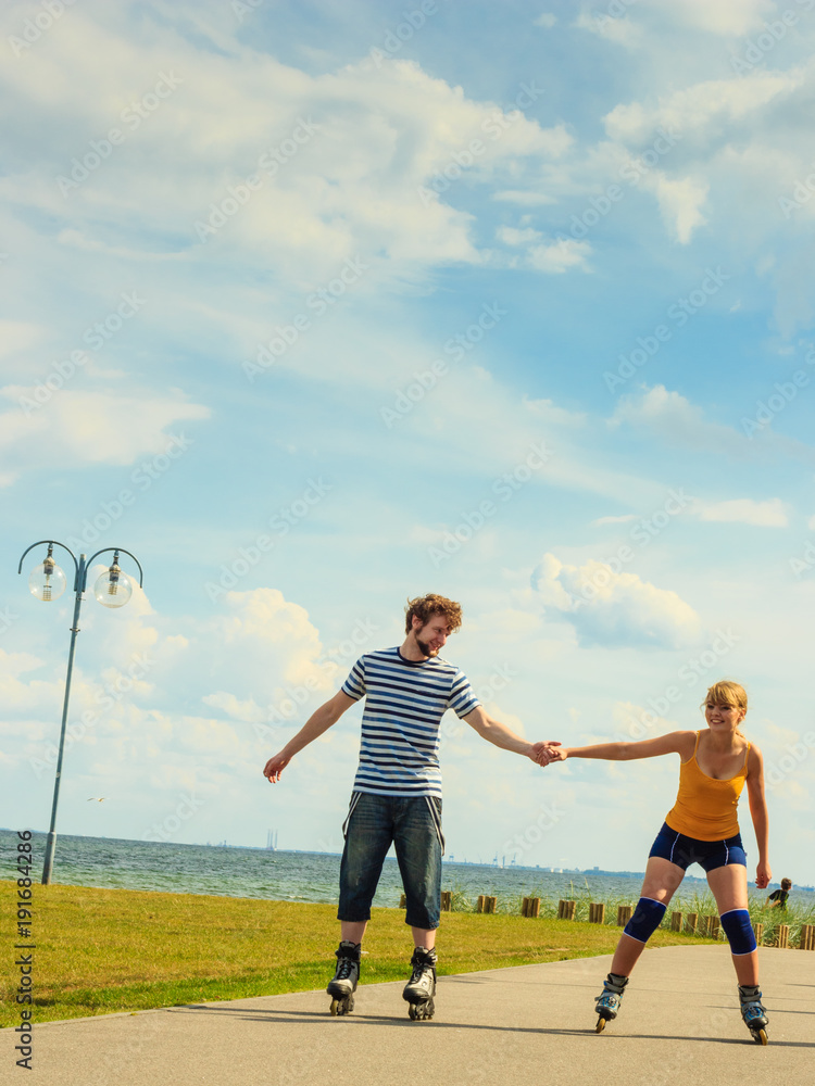 Young couple on roller skates riding outdoors Young couple on roller skates riding outdoors