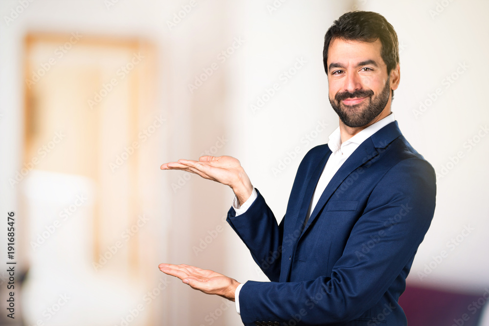 Handsome man presenting something on unfocused background Handsome man presenting something on unfocused background