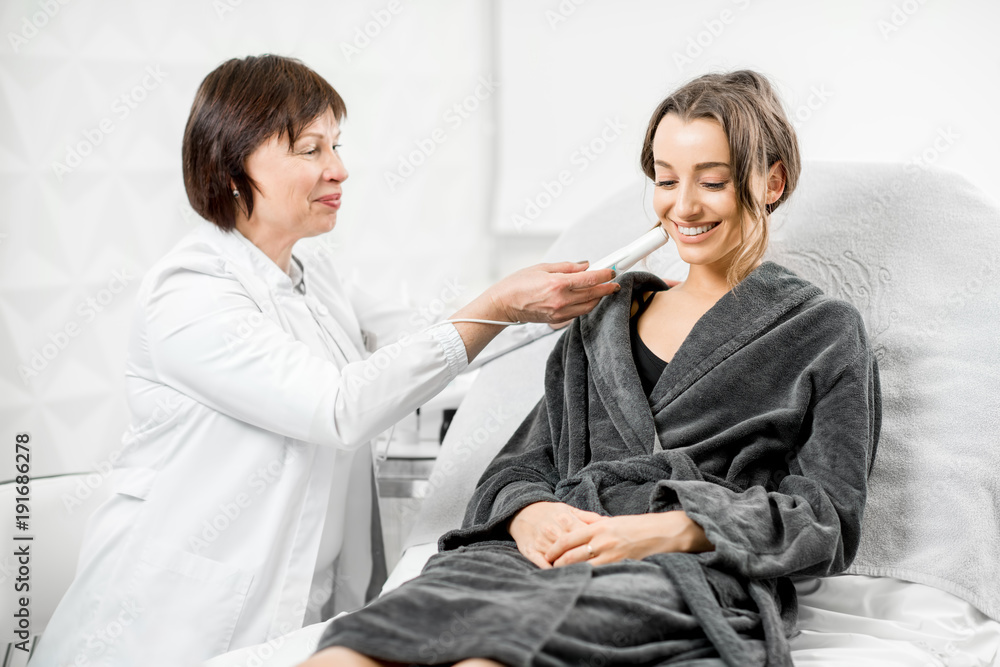 Obraz premium Senior woman cosmetologist measuring skin dryness with professional tool in the medical center