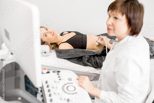 Senior doctor making an ultrasound examination to a young woman patient