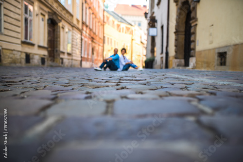 a guy and a girl are on an old cobblestone street in Europe